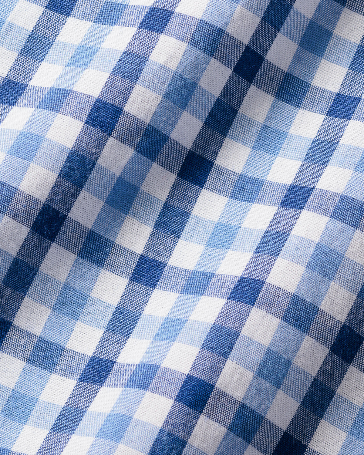 The Girls Twill Amelie Nightgown by Petite Plume showcases a royal blue gingham pattern with alternating light and dark yarn-dyed cotton squares. Soft and textured, this material offers gentle folds, ideal for cozy sleepwear.