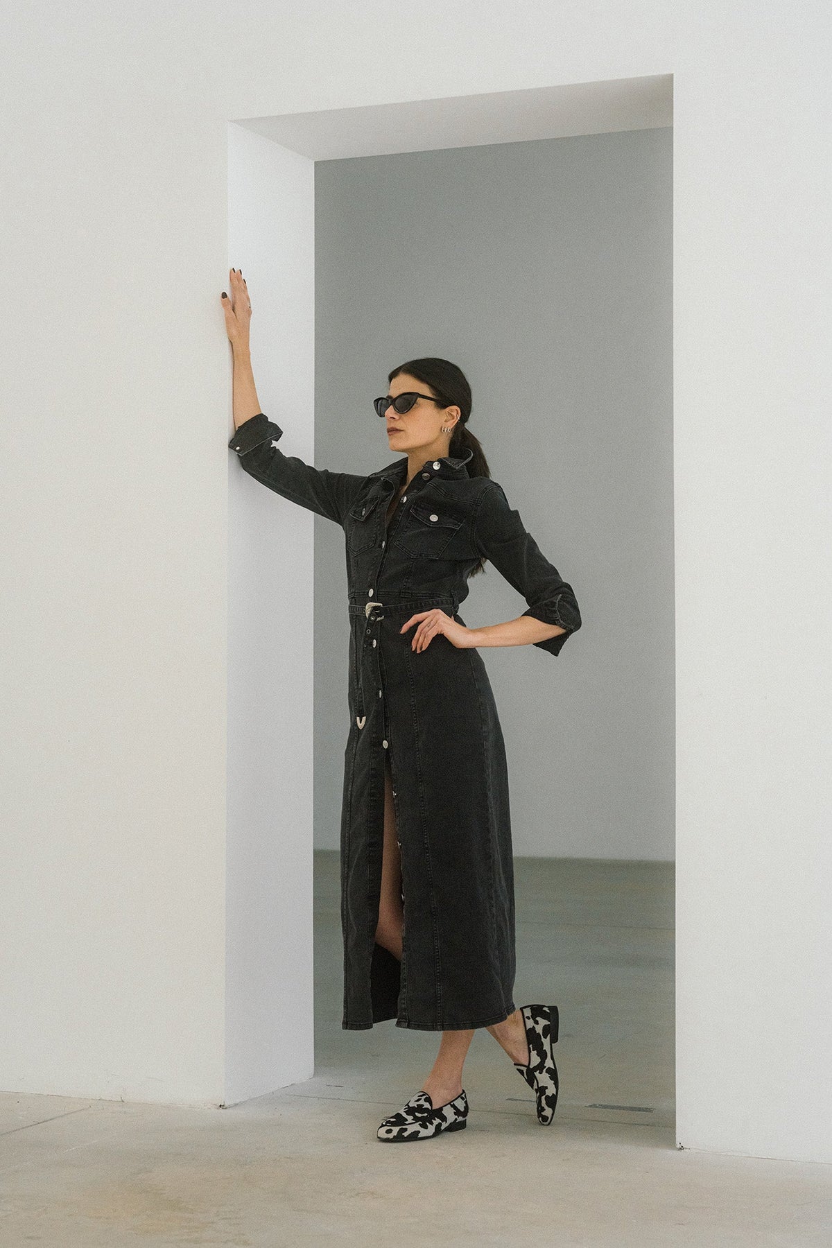 Full-length view of Women’s Cow Print Milano Loafer showcasing black and white cow print uppers on a model in a gray interior