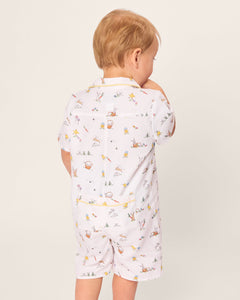 A toddler in Petite Plumes Babys Twill Romper, featuring the Easter Frolic print, gazes to the side. With soft brushed twill fabric showcasing rabbits and gardening tools, the light-haired child enjoys short sleeves and shorts in this charming attire.