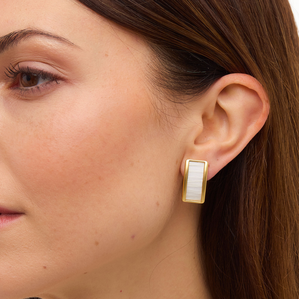 Close-up of Smith Town stud earring on model’s ear showcasing a rectangular gold frame with white rooster-feather inlay