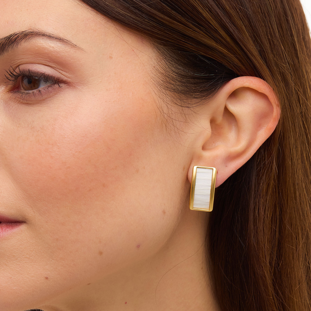 Close-up of Smith Town stud earring on model’s ear showcasing a rectangular gold frame with white rooster-feather inlay