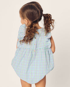 A young child with curly pigtails, facing away, wears Petite Plumes Babys Twill Ruffled Romper in Spring Gingham featuring buttons down the back and flutter sleeves against a plain, light background.