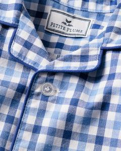 A close-up of the Babys Twill Summer Romper in Royal Blue Gingham by Petite Plume shows a collar with a fabric label, blue piping, and soft brushed fabric. A white button is fastened in the center.