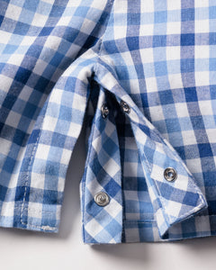 Close-up of Petite Plumes Babys Twill Summer Romper in Royal Blue Gingham, highlighting the metal snap buttons. The yarn-dyed cotton fabric is slightly folded to reveal detailed stitching and button features.