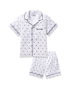 The Kids Twill Short Sleeve Short Set by Petite Plume features a white pajama outfit in premium cotton with a charming Buzzing Bees print, including a short-sleeved button-up shirt, chest pocket, and shorts, all elegantly finished with dark piping.