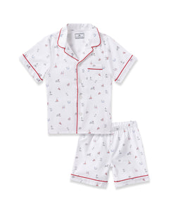 The Kids Twill Short Sleeve Short Set in Coastal Charms by Petite Plume offers white pajamas adorned with sails, anchors, and bicycles. Featuring red piping and a chest pocket, these stylish pieces offer both luxury and flame retardant safety.
