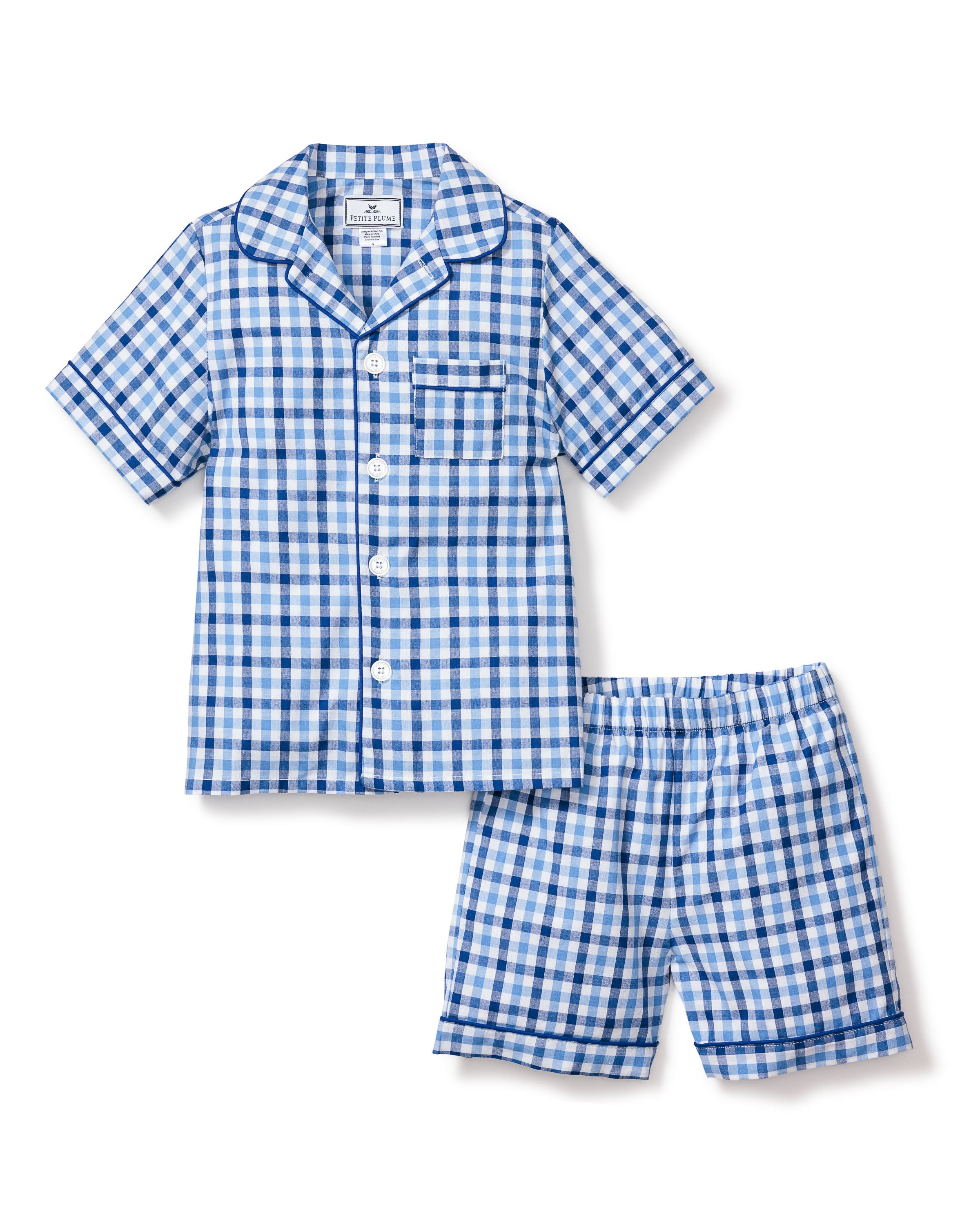 The Kids Twill Pajama Short Set by Petite Plume, in Royal Blue Gingham, showcases a luxury sleepwear style. Featuring short sleeves and a collared top with front pocket, its perfectly paired with matching shorts for ultimate comfort.