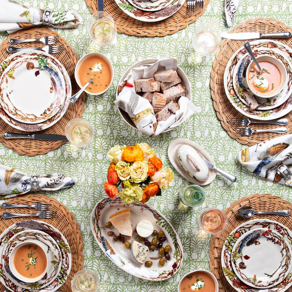 Forest Walk coupe bowls serving soup on braided placemats at a styled dining table with bread, cheese, and floral centerpiece