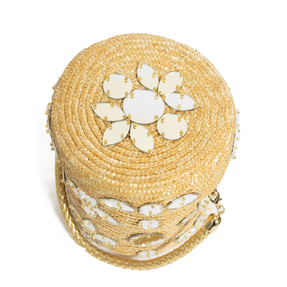 Top-down view of Shisha Cylinder bag in natural raffia with mirrored floral applique, gold beads, and braided metallic handle