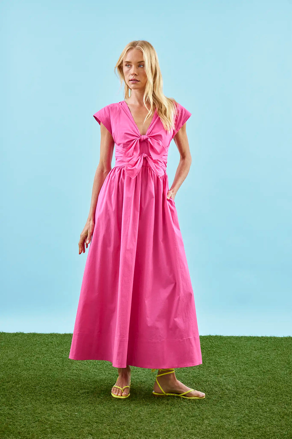 The Calista Dress in bright fuchsia has a tie-front bodice and full skirt.