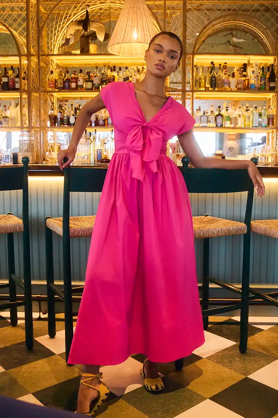 The Calista Dress in bright fuchsia has a tie-front bodice and full skirt.