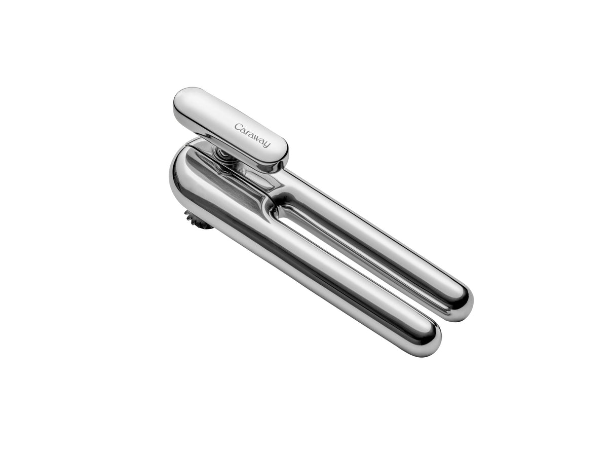 Three-quarter top view of Caraway stainless steel can opener showcasing ergonomic rounded handles and precision cutting wheel on white background