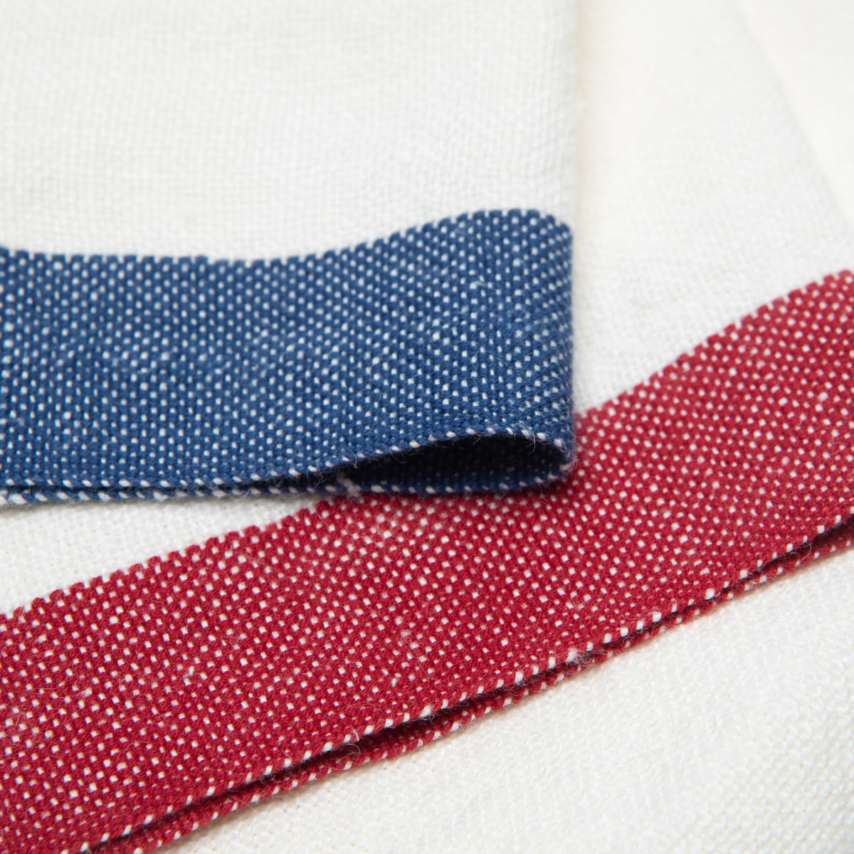 Close-up of Paris linen napkins set of 2 showcasing blue and red woven borders and textured white weave