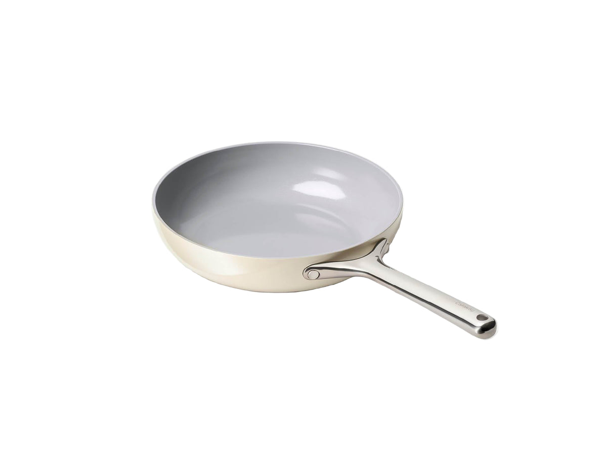 Angled top-down view of Caraway 10.5in cream fry pan showing light-gray ceramic nonstick interior and stainless steel handle
