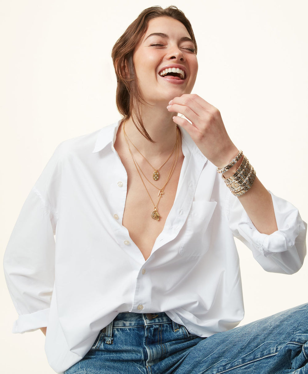 Close-up of The Stud Bracelet set of three on a model’s wrist showing mixed metal enamel stretch bracelets on a white shirt