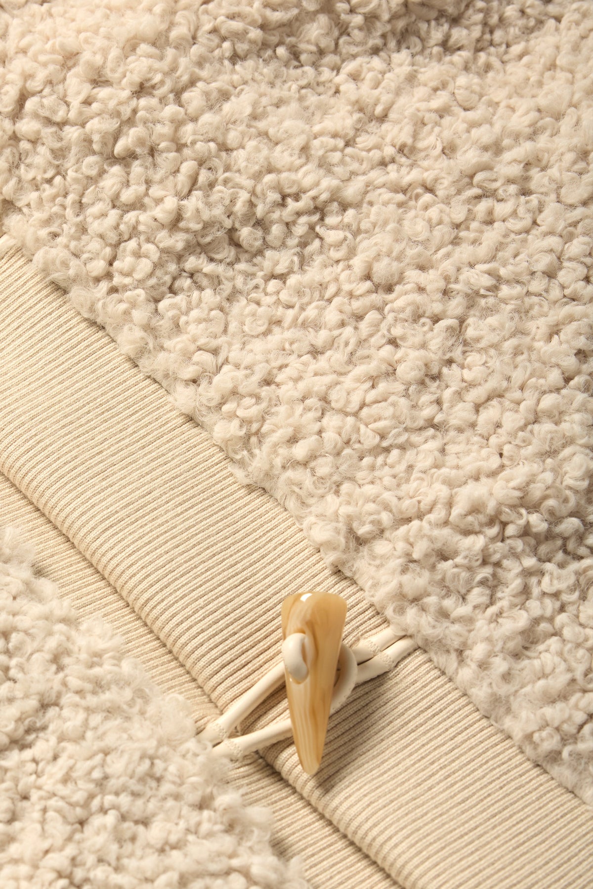 Close-up of a beige sherpa skirt with a decorative button on the waistband 