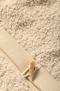 Close-up of a beige sherpa skirt with a decorative button on the waistband 