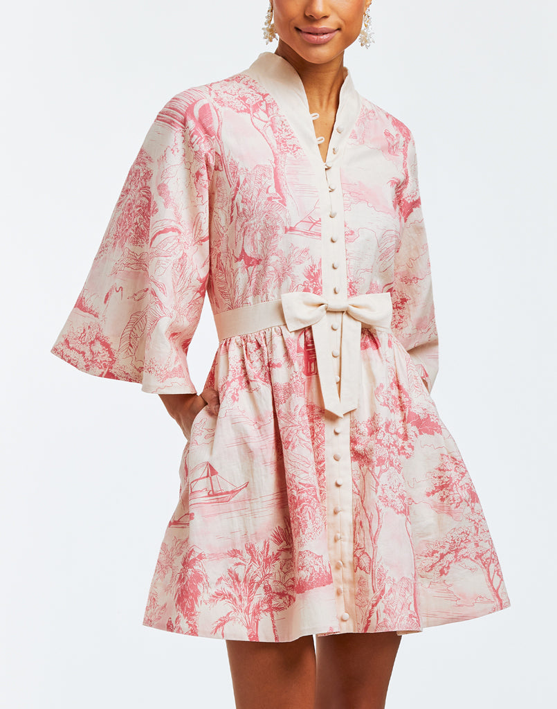 Linen mini dress with butterfly sleeves, hand pockets, and front bow detail. Featuring a mandarin collar and a pink toile print. 