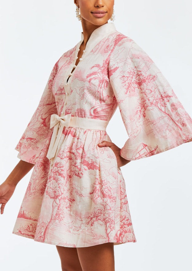 Linen mini dress with butterfly sleeves, hand pockets, and front bow detail. Featuring a mandarin collar and a pink toile print. 