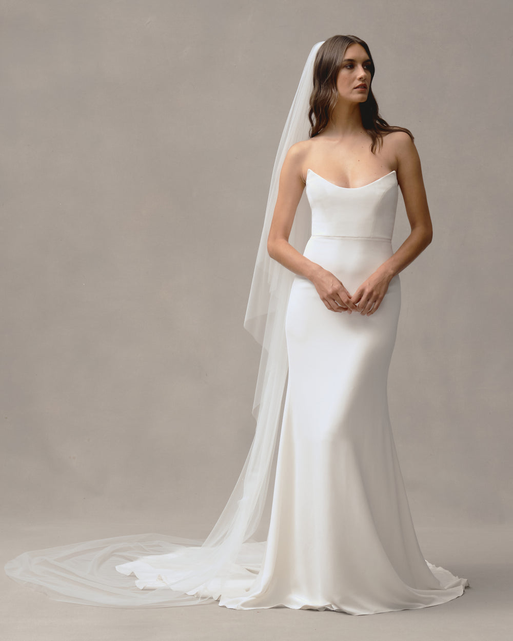 Front view of Cascade veil showcasing cathedral-length illusion tulle and waterfall edge draping behind a model on a neutral gray backdrop