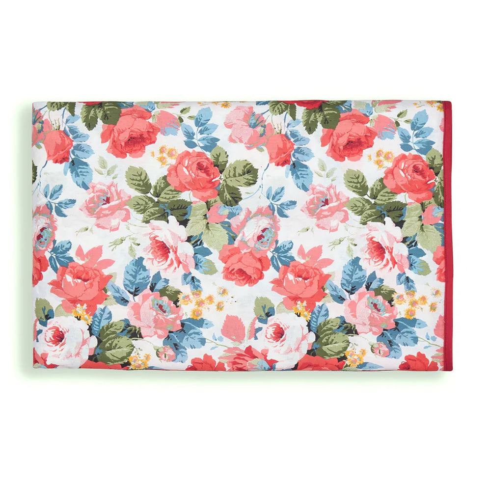 Folded Charlotte tablecloth showcasing coral and pink rose floral print with blue and green leaves on white background