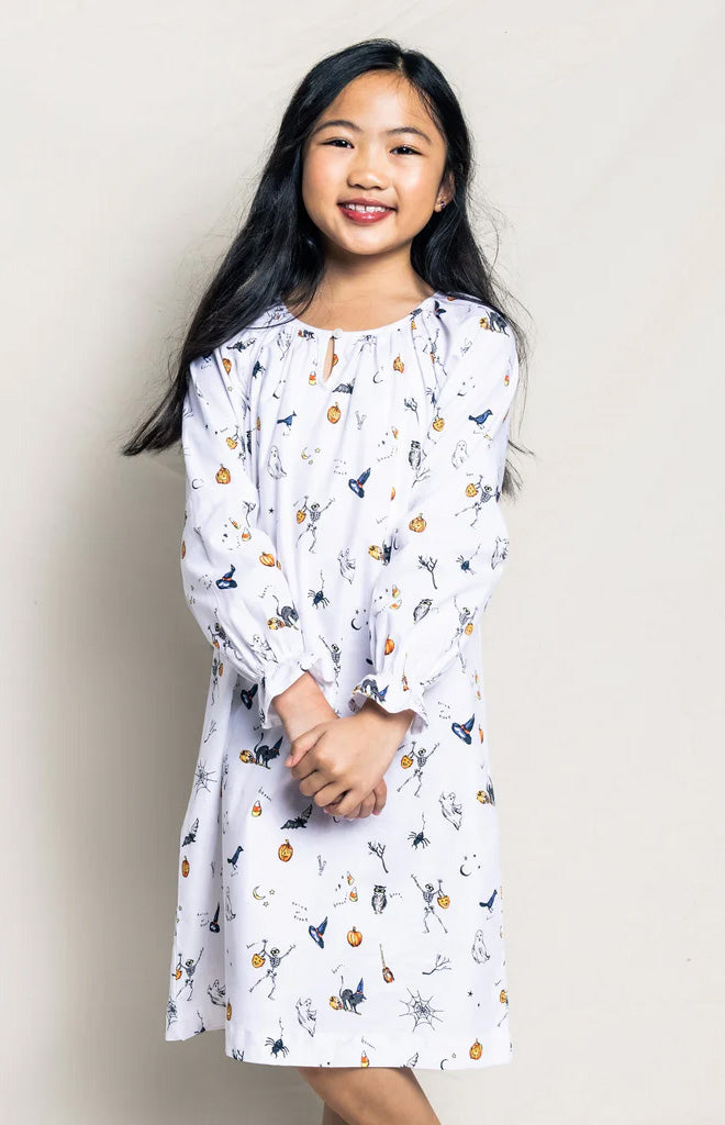 Front view of Children’s Trick or Treat Delphine nightgown on child model showcasing long sleeves, gathered neckline, and Halloween print on neutral beige background
