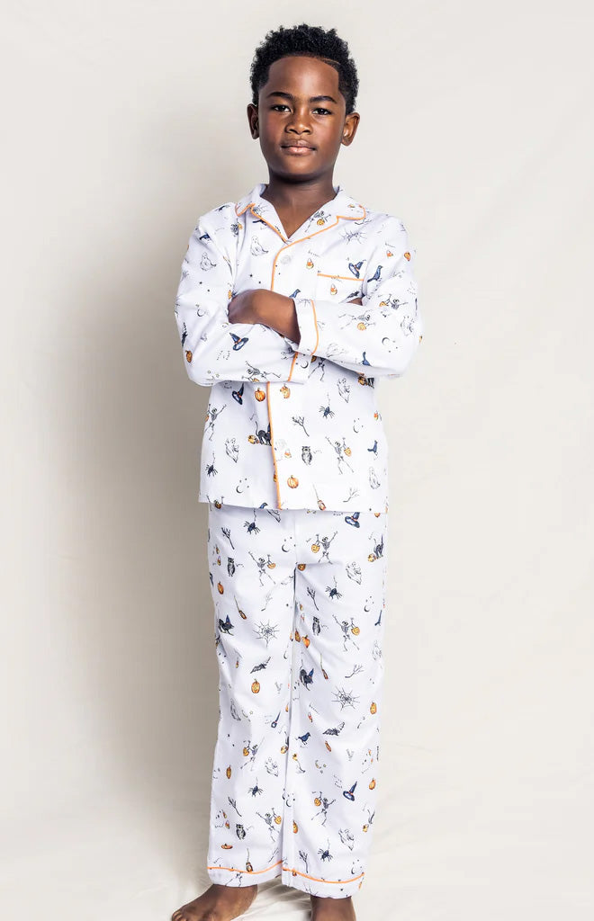 Full-length front view of children’s Trick or Treat pajama set on a child model, white brushed cotton with Halloween print and orange contrast piping on a light background