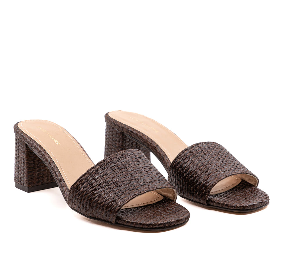 Three-quarter view of Claudia raffia mule in brown with woven upper, 50mm block heel and round toe on white background