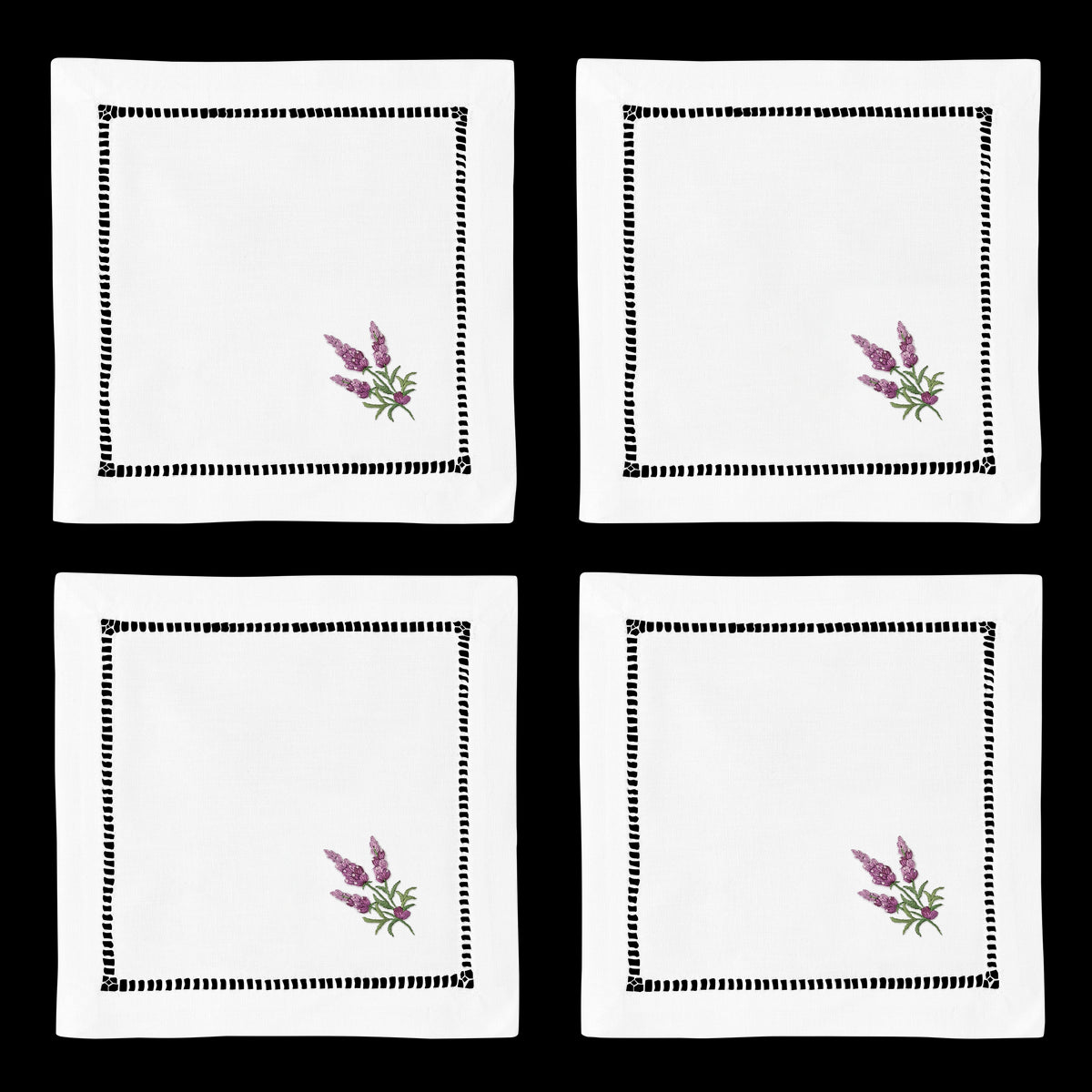 4 white cocktail napkins. Embroidered in the bottom right corner of each is a bundle of lavender