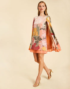Collins Cape Mini Dress in Painted Blooms sequin with a boat neckline, draped cape, and flutter hem.
