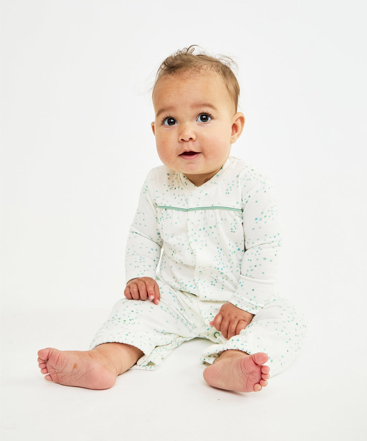 Front view of Convertible Gown in Seafoam Star on a seated baby showcasing seafoam star print and signature green piping on white background