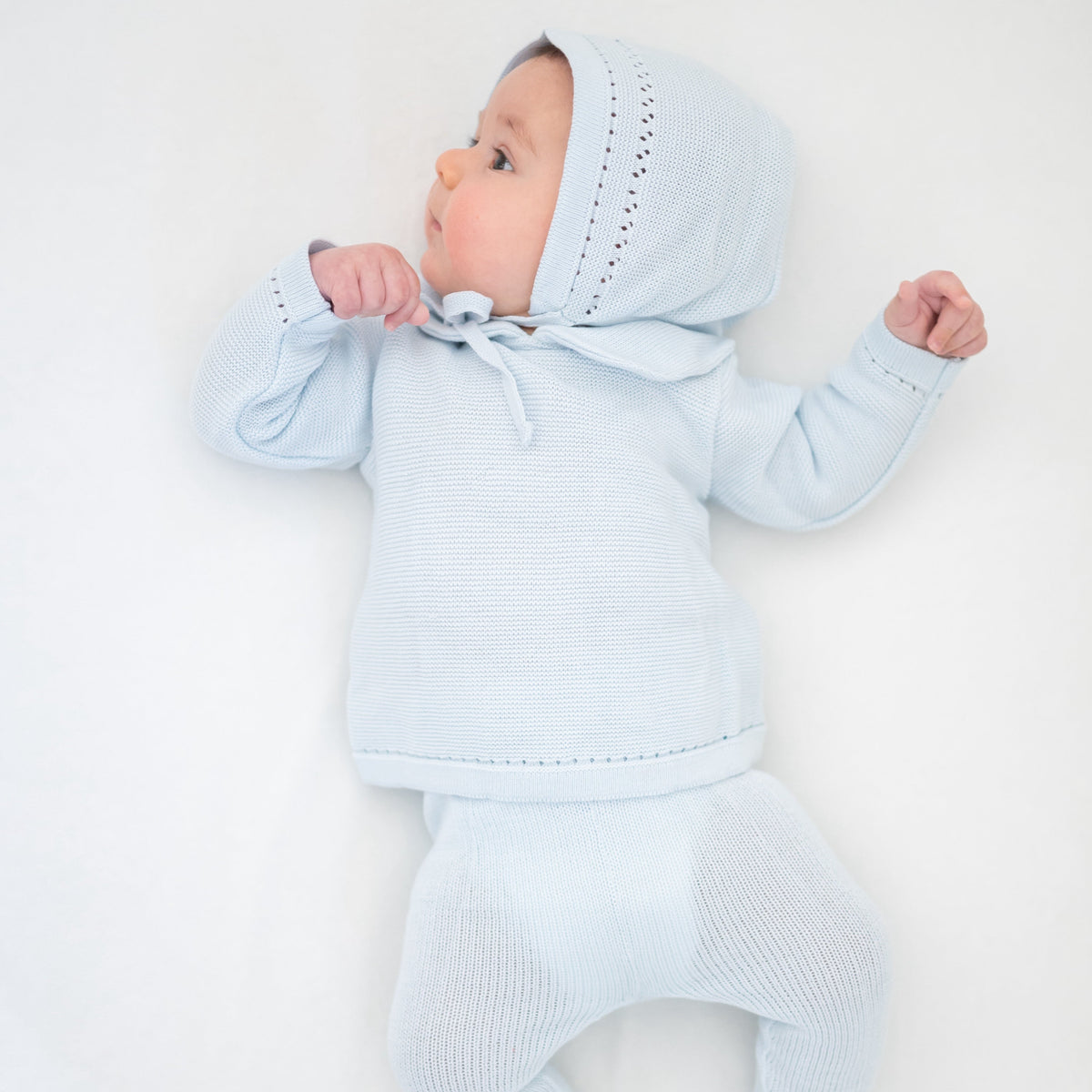 Side view of Knit Baby Bonnet in Light Blue showcasing its tie fastening with a white background