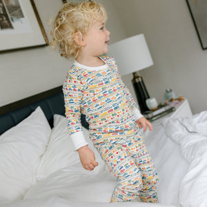 Side view of colorful cars and trucks two piece pajamas on a child in a bedroom