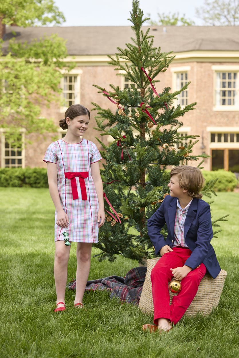 Little English classic children's clothing. Girls A-line dress in red and green plaid with red bow and red piping detail for the holidays.  Boys Douglas Plaid button down shirt with red corduroy pants and navy wool blazer.