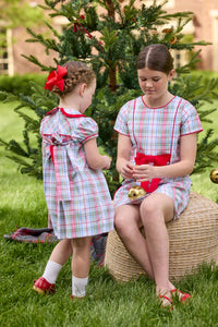 Little English classic children's clothing. Girls A-line dress in red and green plaid with red bow and red piping detail for the holidays.  Matching toddler girl dress with ruffled peter pan collar and bow tie sash in back.