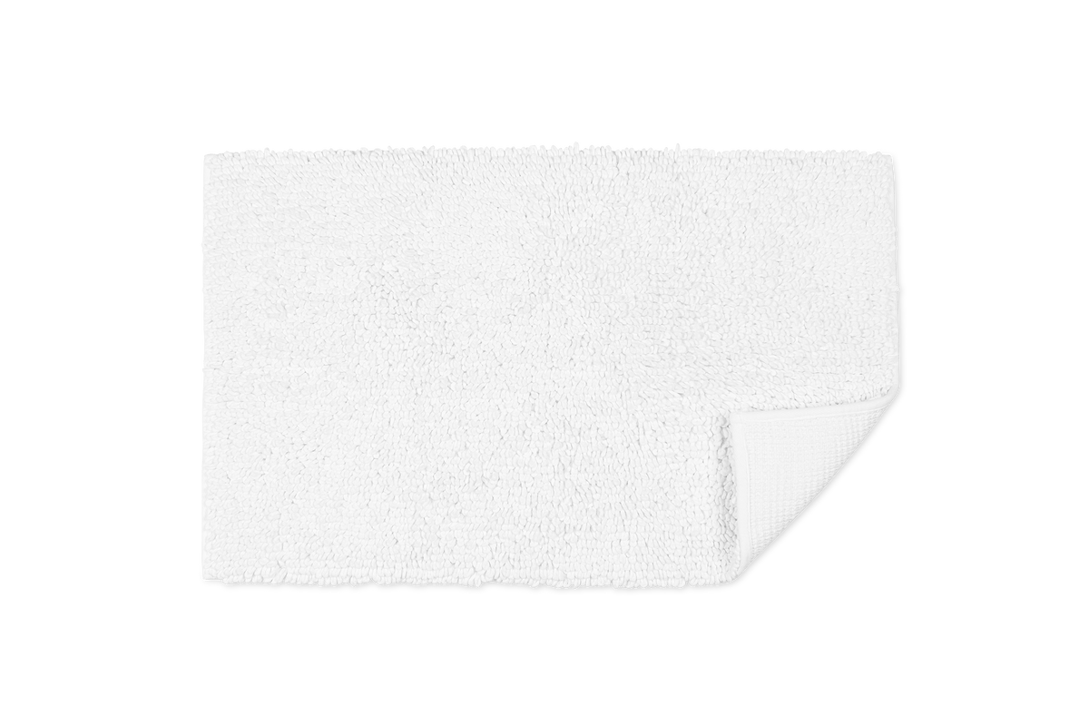 Top down view of Costas rug showing chunky looped cotton pile and folded corner with non slip backing on white