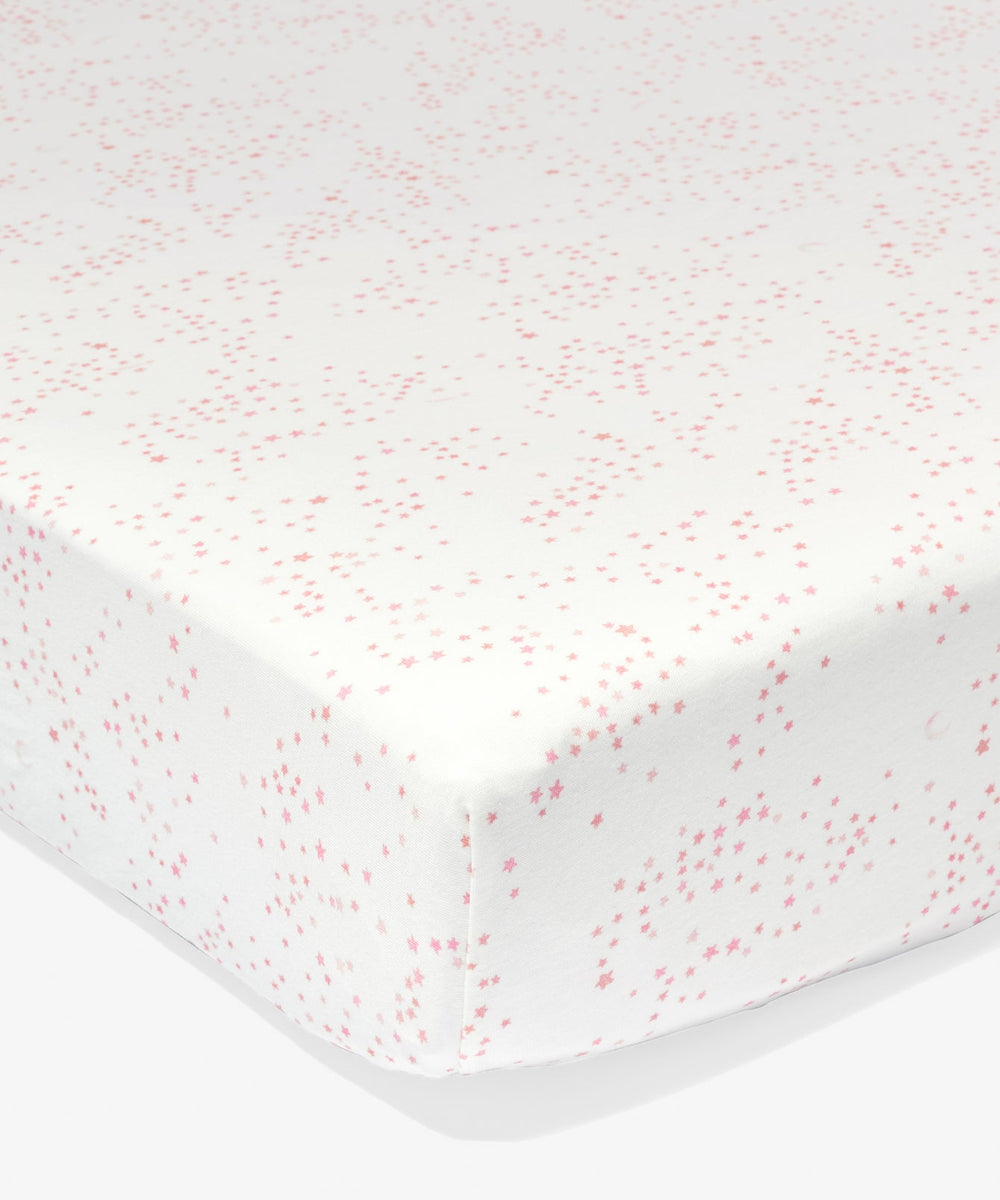 Close-up of Crib Sheet in Tulip Star showcasing pink star pattern and fitted deep-pocket corners on a white background