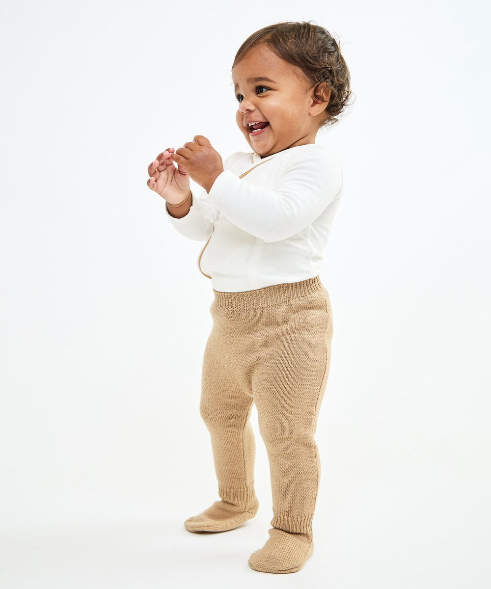 Three-quarter view of Crissy Baby Pant in Camel showing ribbed waistband and footed knit on a white background