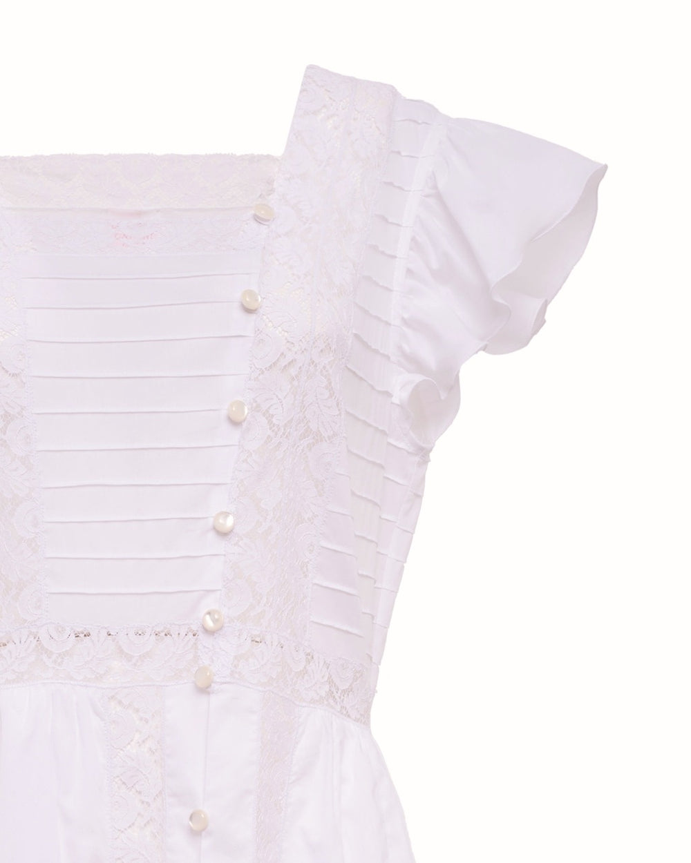 Close-up of Numana dress bodice in optical muslin showing lace intarsia, pintuck panel, pearl buttons and ruffled cap sleeve