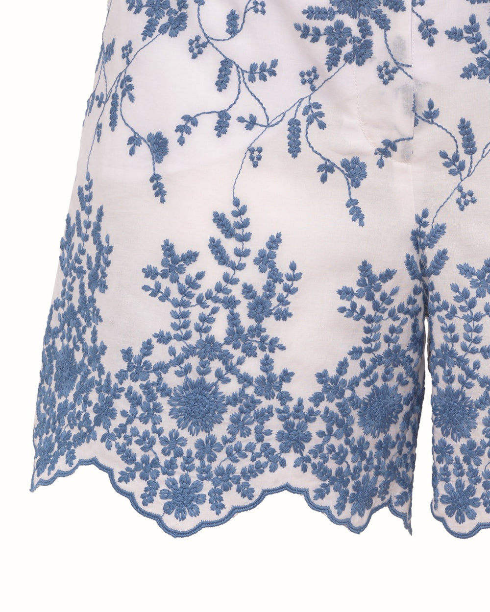 Close-up of Rocchetta short showing blue floral embroidery and scalloped hem on white sangallo cotton