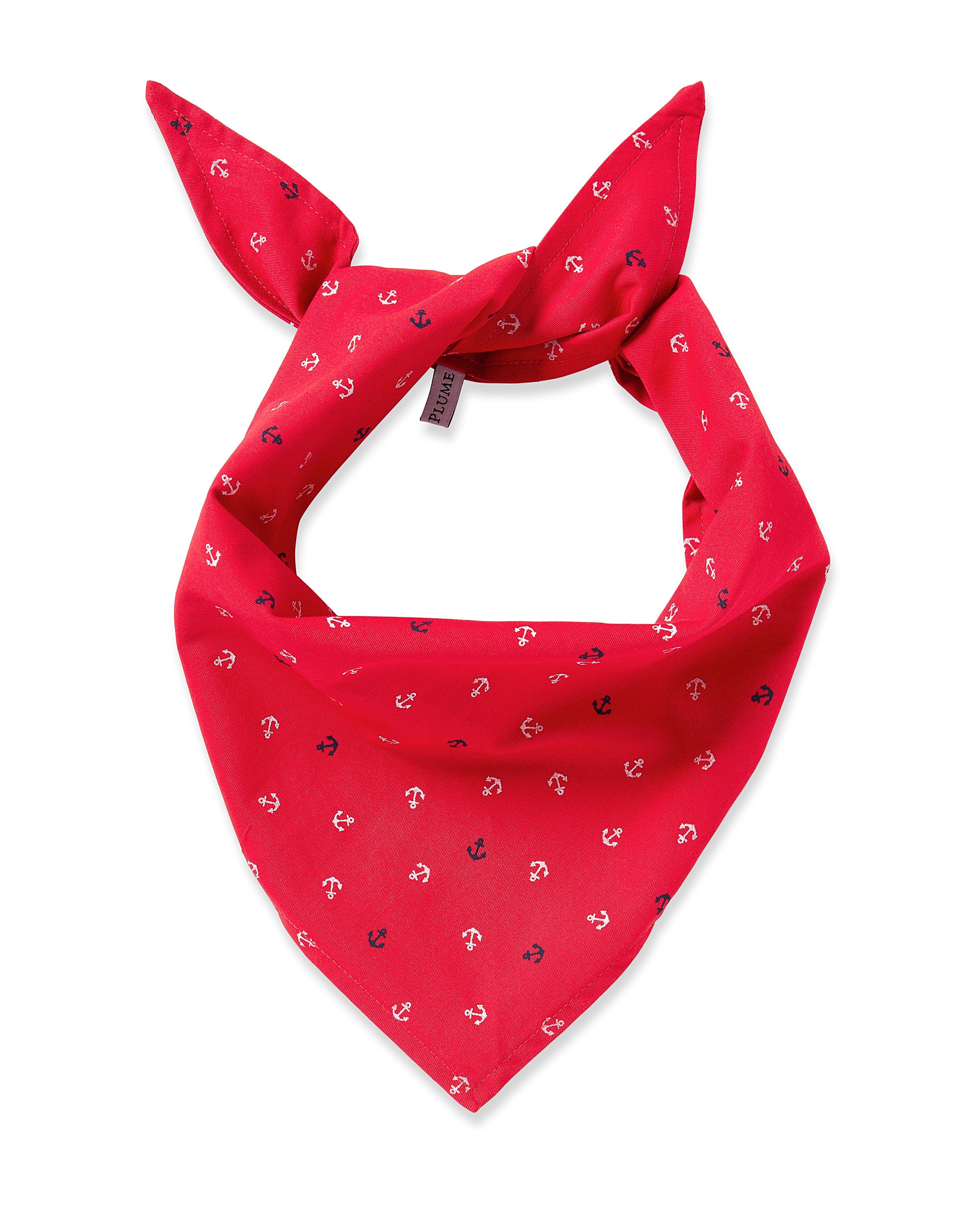 A charming red Petite Plume Dog Twill Bandana in Anchors Away is adorned with small white and navy blue anchor patterns. Tied in a knot to form two pointy ends, its perfect as a stylish dog bandana and a must-have accessory with the fabric label visible on one side.