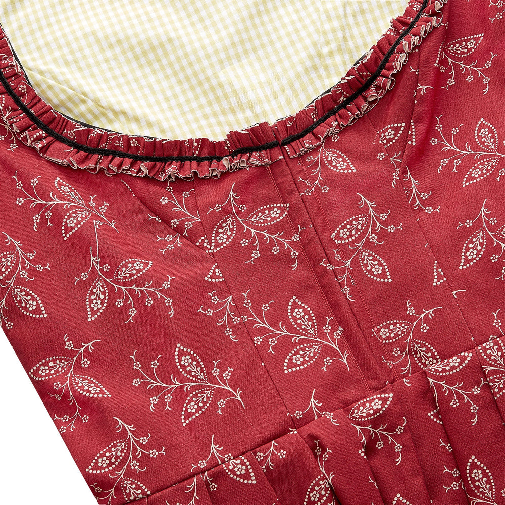 Close-up of Camilla Dress bodice showcasing red floral-print cotton, ruffled neckline with black velvet trim and yellow gingham lining