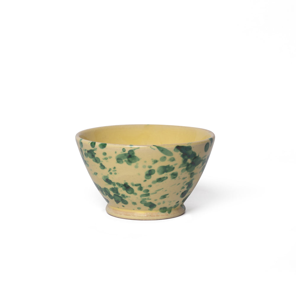 Three-quarter view of small Splatter Bowl showcasing yellow glaze with green splatter pattern on white background