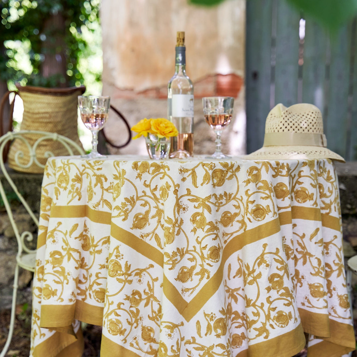Front view of French Tablecloth Granada Mustard showcasing mustard pomegranates and intertwined floral pattern on a styled dining table