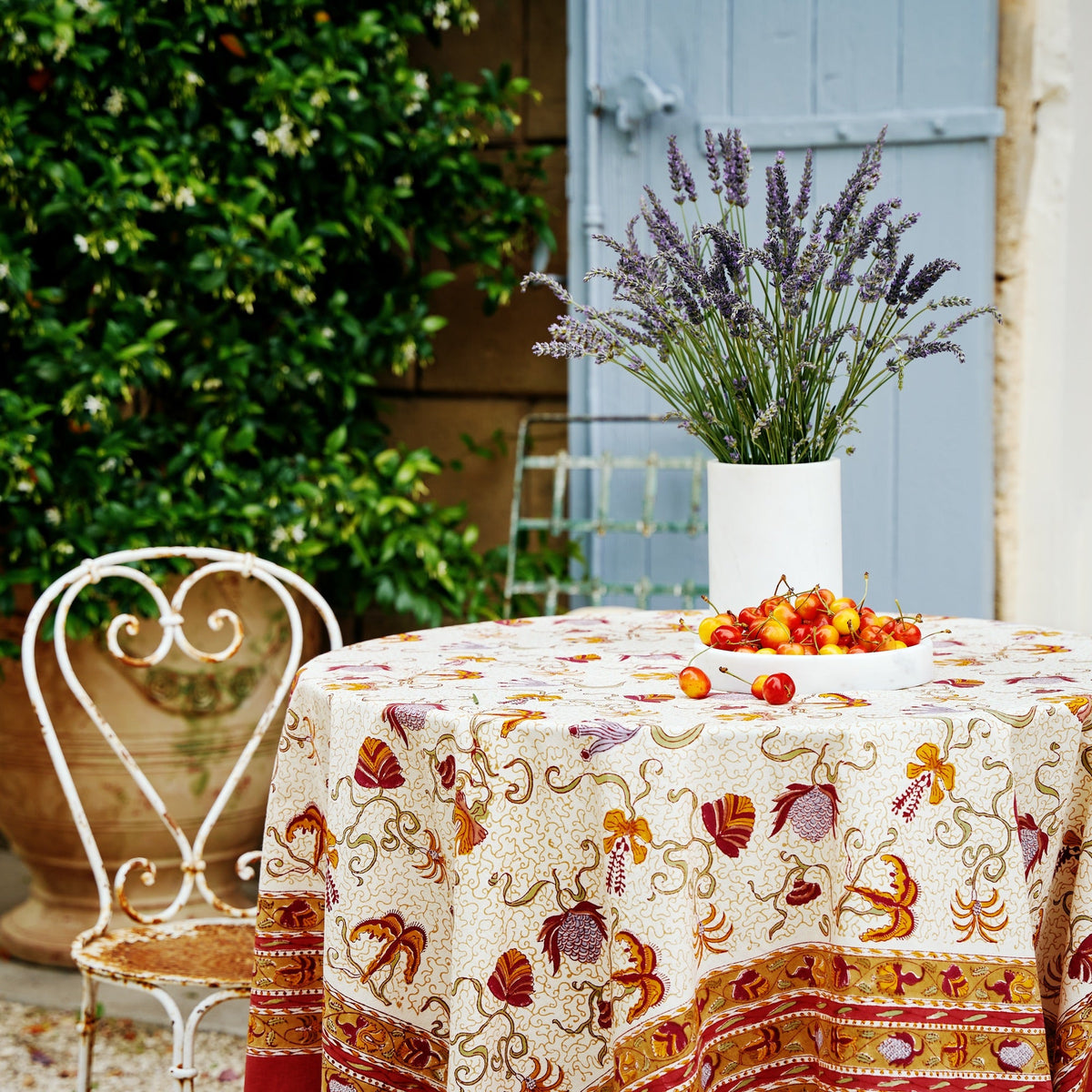 Styled view of French Tablecloth Fleur des Indes showcasing rich harvest tones and exotic floral motifs with garden setting