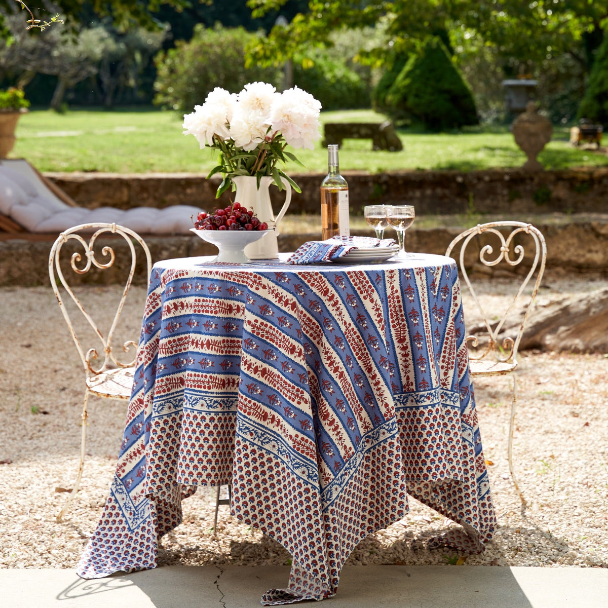 Front view of French Tablecloth Avignon Red & Blue showcasing botanical pattern on an outdoor dining table