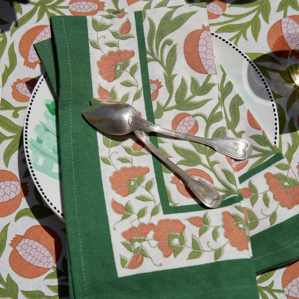 Close-up of Grenadine Orange & Green Napkins, Set of 6 showcasing floral pattern and green borders on a table
