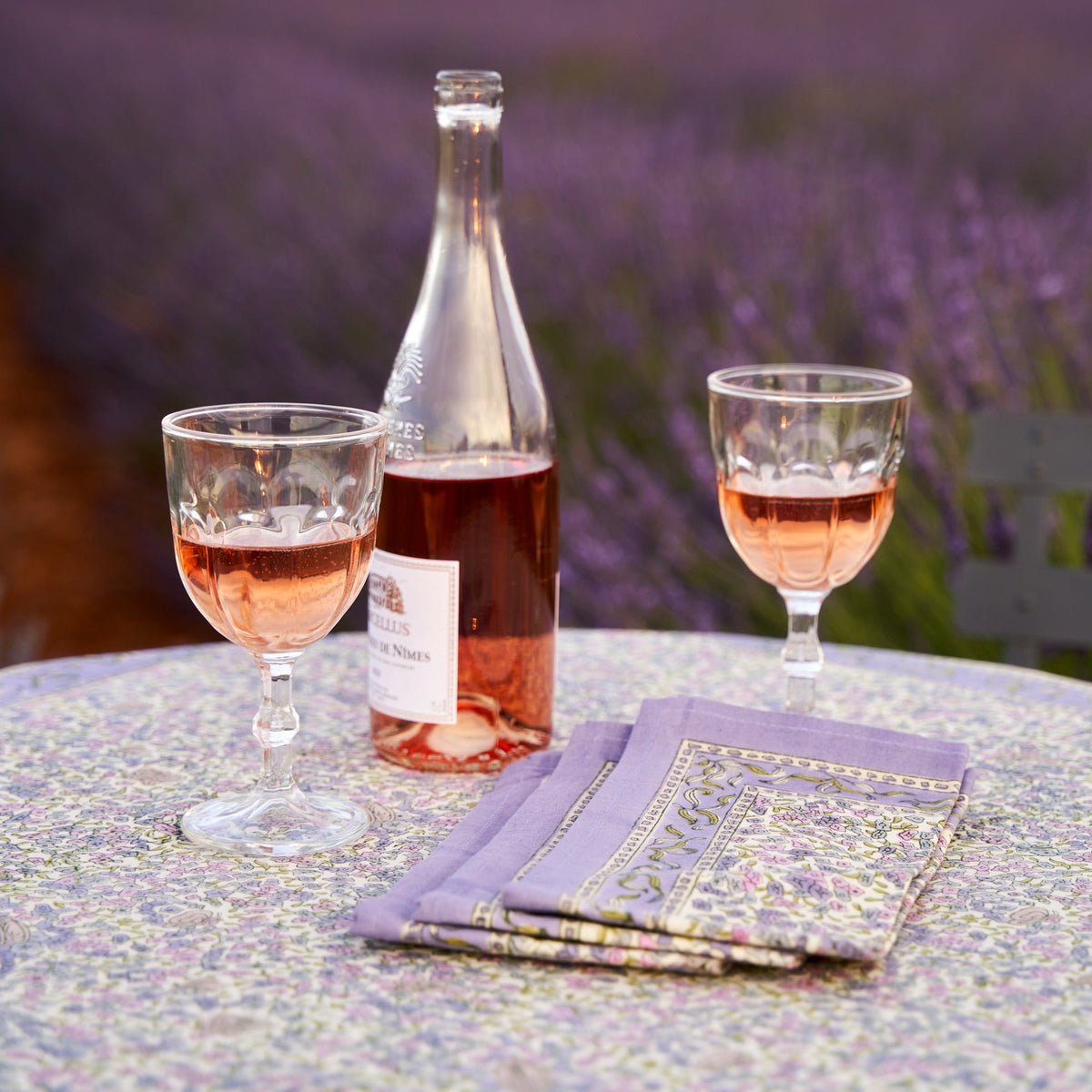 Lavender patterned napkins arranged on a table with rose wine and glasses against lavender flowers