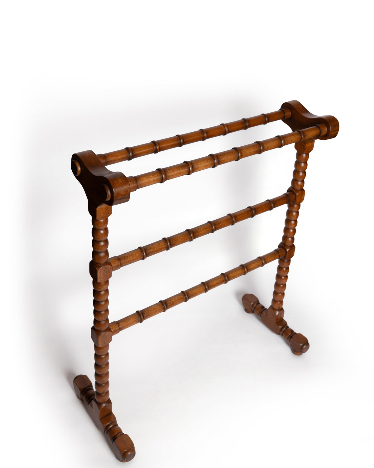 Angled front view of mahogany clothes horse showing turned spindle rails and carved feet on white background