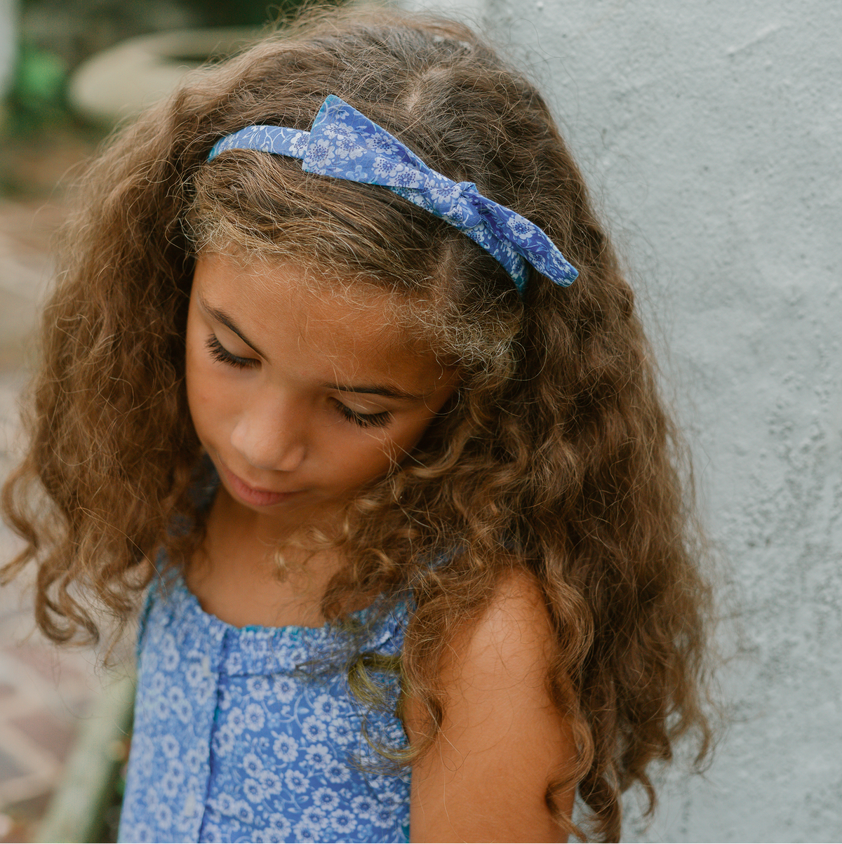 Close up of Girls Headband Set In Rosebay And Lavender Stripe showcasing a floral bow on a child with a blurred background